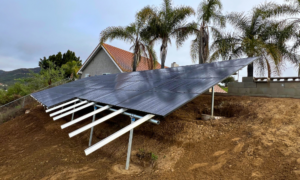 Ground-mounted solar panels installed near a home surrounded by palm trees, highlighting Suncovia’s sustainable solar energy solutions.