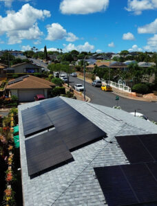 Solar panels on top of a roof with the neighborhood shown in the background.