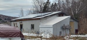 Durable solar panels installed by Suncovia on a rural metal building, optimizing energy efficiency and sustainability in a snowy landscape.