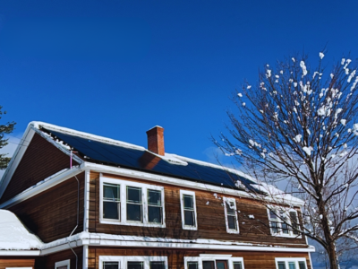 Going solar in New England winter with solar panels installed on a snow-covered house, generating energy even in snowy conditions.