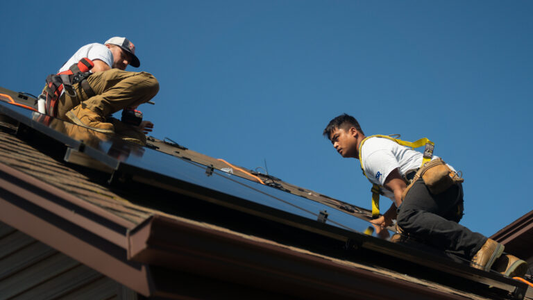 two Suncovia workers placing solar panels