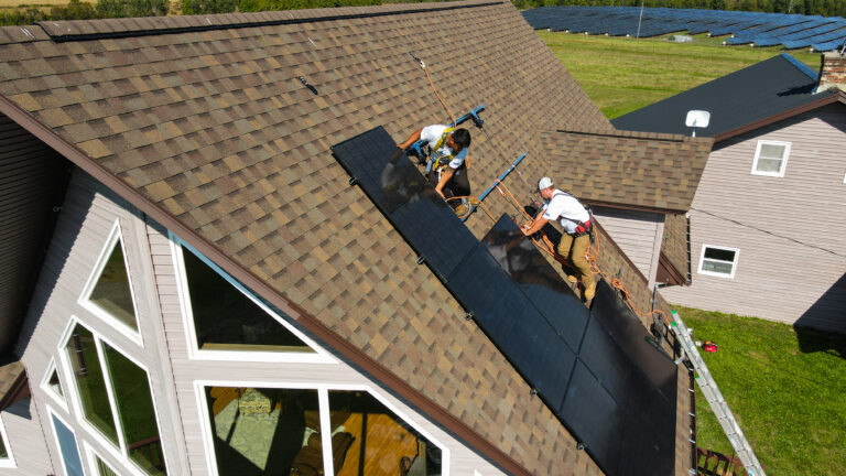 big shingles house two suncovia workers installing new solar panel
