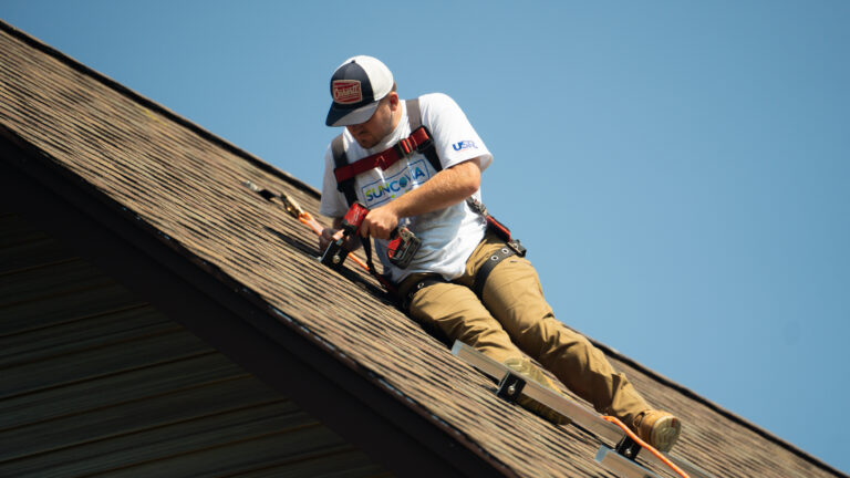 worker on top of shingles fixing roof