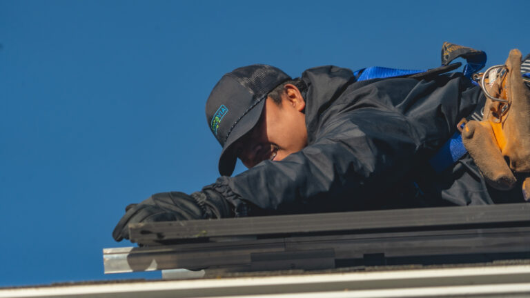 worker installing solar using both hands